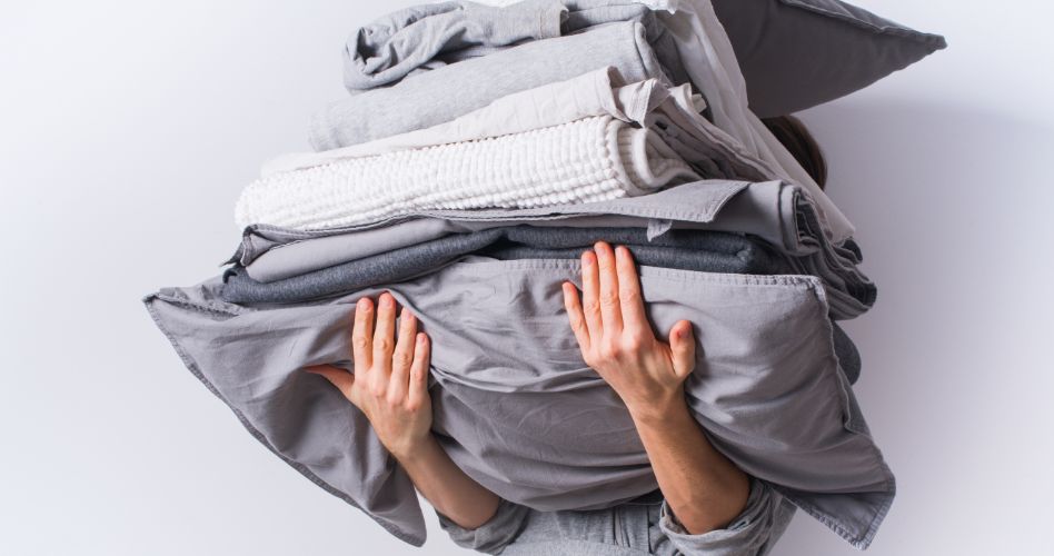 Whirlpool Combination Microwave Une personne tient une pile de draps contours gris pliés